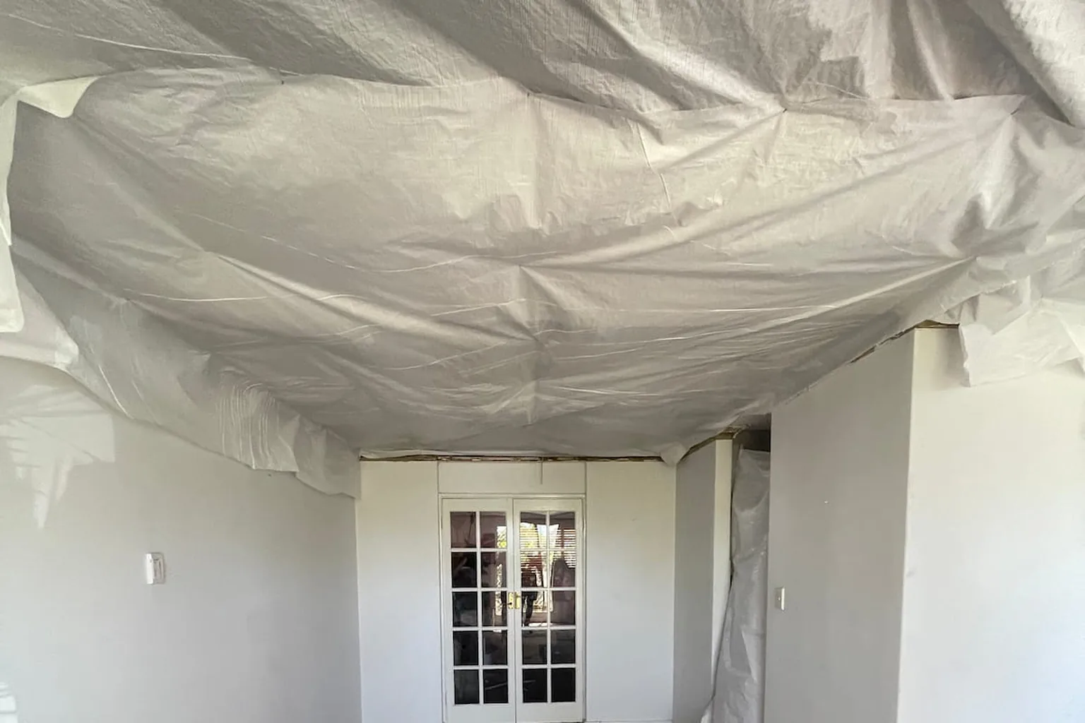 A failing ceiling made safe with sheeting catching the debris below it